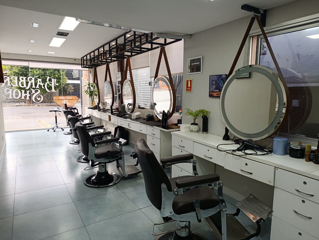 Barbearia com cadeiras de couro e espelhos redondos