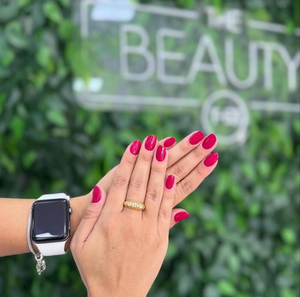 Unhas pink diante da parede com o logo The Beauty